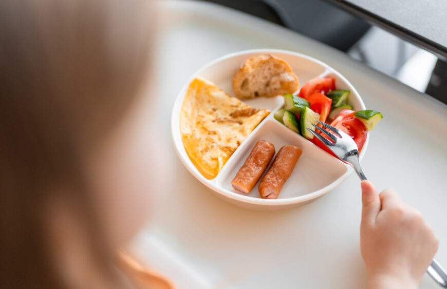Little girl have a balanced breakfast in home kitchen in the morning