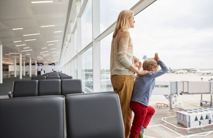 mother-and-sons-in-departure-lounge-looking-out-of-2025-04-03-05-26-04-utc