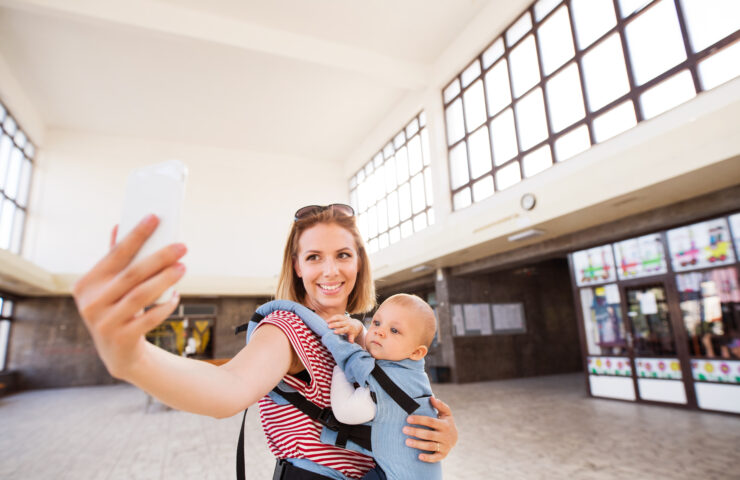 Young mother with smartphone and baby travelling.