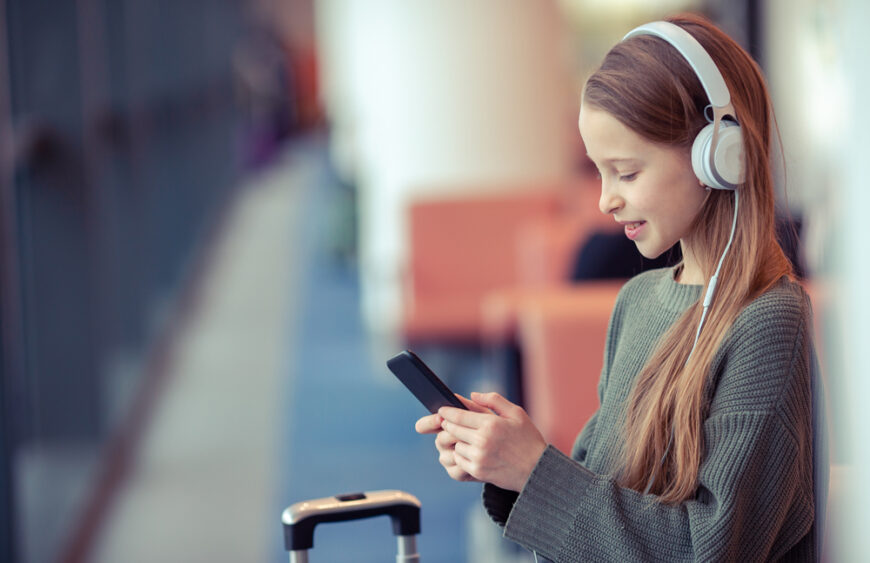 Adorable little girl at airport in big international airport near window