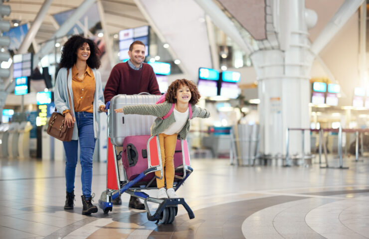 Airport, family and child excited for flight with suitcase troll