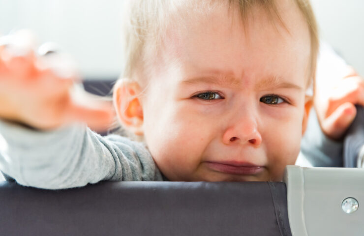 Portrait of one year old baby girl crying and reaching hand towards camera.