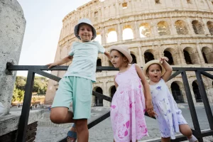 Three funny kids against Colosseum in the old city center of Rom