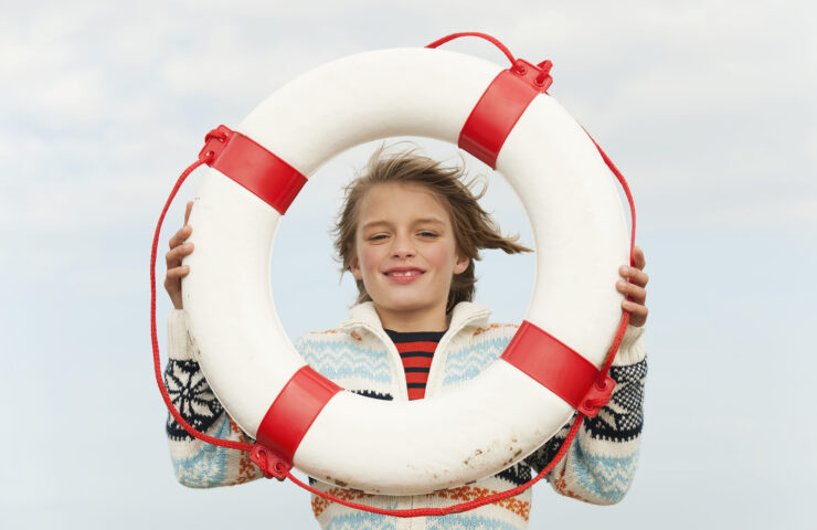Germany, North Sea, St.Peter-Ording, Boy (8-9) holding life saver at beach, smiling, portrait
