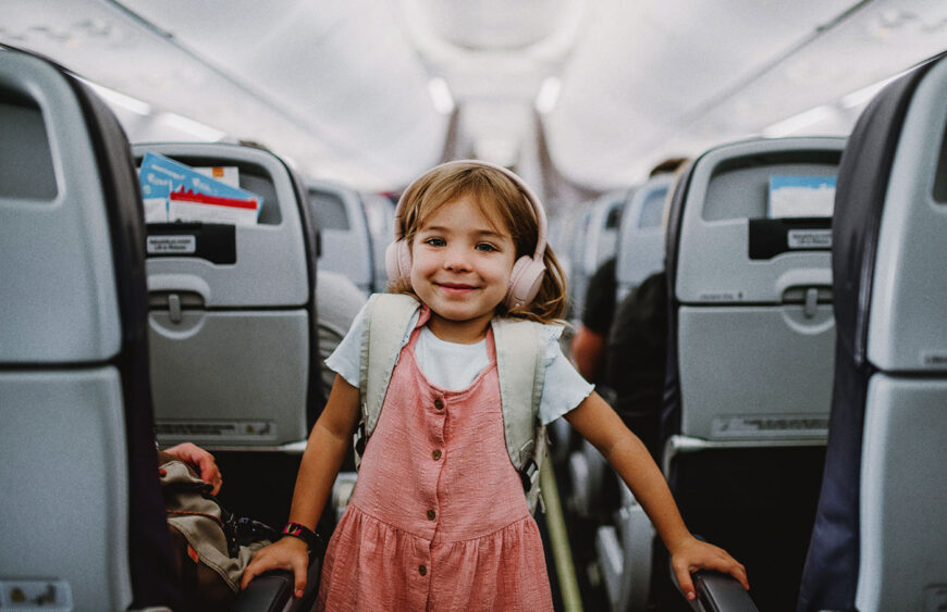 happy-little-girl-standing-in-aisle-in-the-plane-2024-10-18-09-32-13-utc