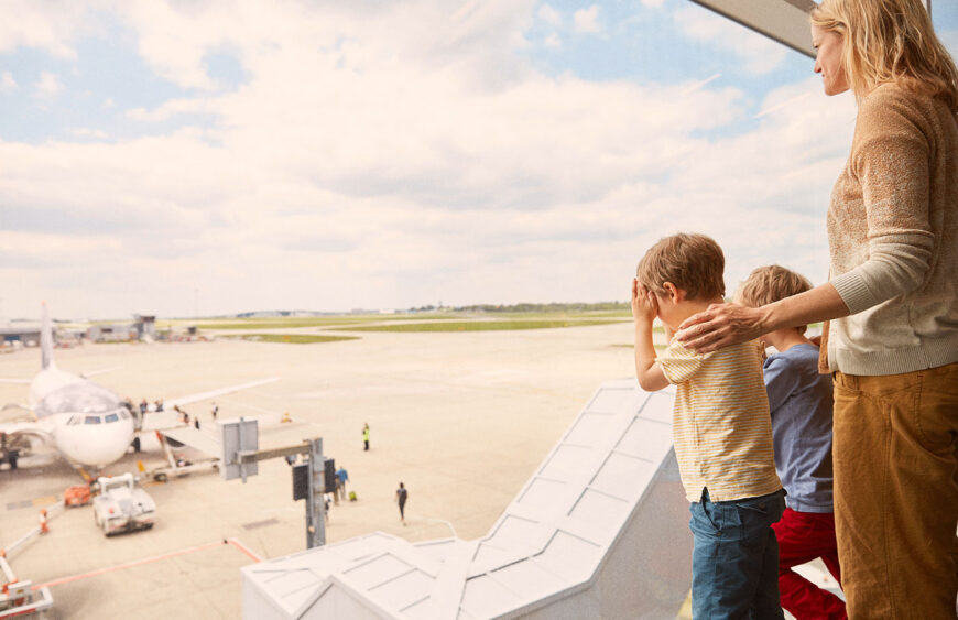 mother-and-sons-looking-out-of-airport-window-2024-11-03-03-33-15-utc