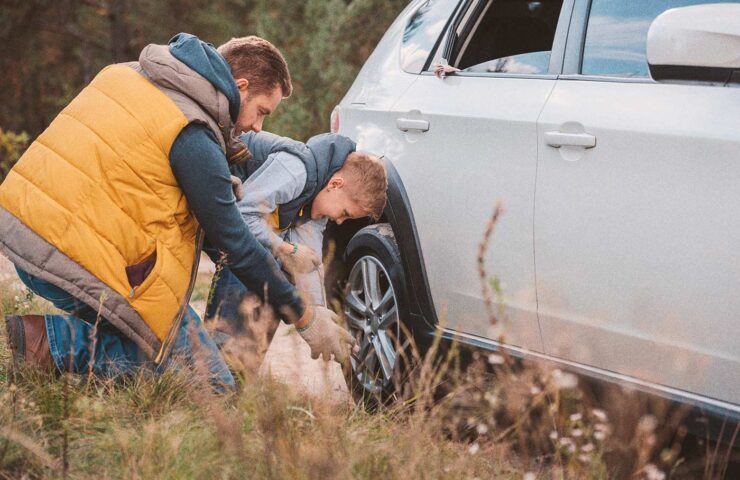 smiling-little-boy-with-father-changing-car-wheel-2024-11-19-13-07-49-utc