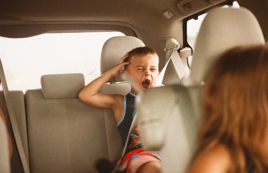 young-boy-in-backseat-of-vehicle-yawning-while-on-2025-01-08-23-25-51-utc