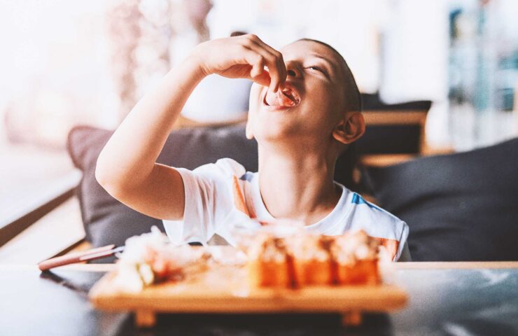 boy-enjoys-eating-sushi-rolls-in-outdoor-cafe-2025-01-26-04-57-01-utc