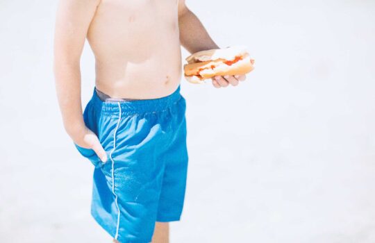 boy-on-beach-holding-a-hotdog-2024-09-19-19-14-40-utc