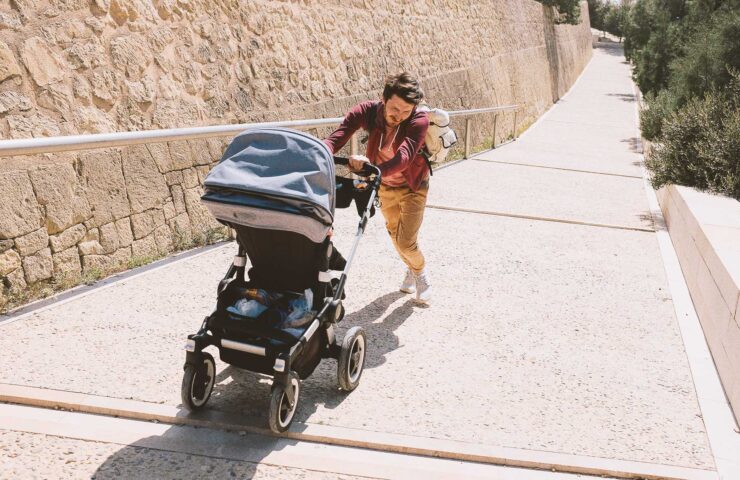 father-rolls-a-stroller-up-the-hill-2024-10-17-07-43-32-utc