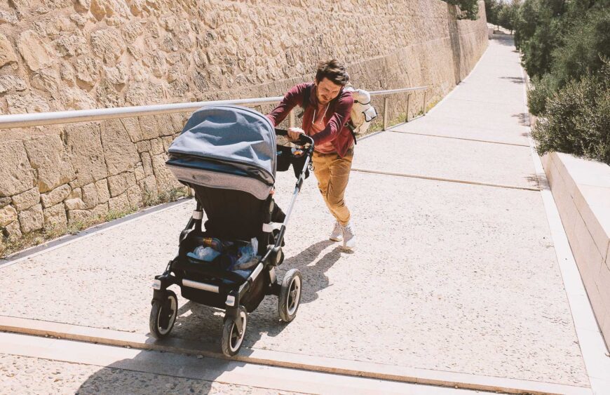 father-rolls-a-stroller-up-the-hill-2024-10-17-07-43-32-utc