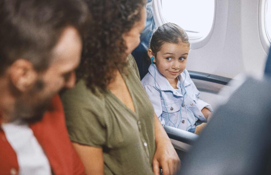 smiling-girl-with-headphones-on-airplane-with-fami-2026-03-10-01-09-30-utc